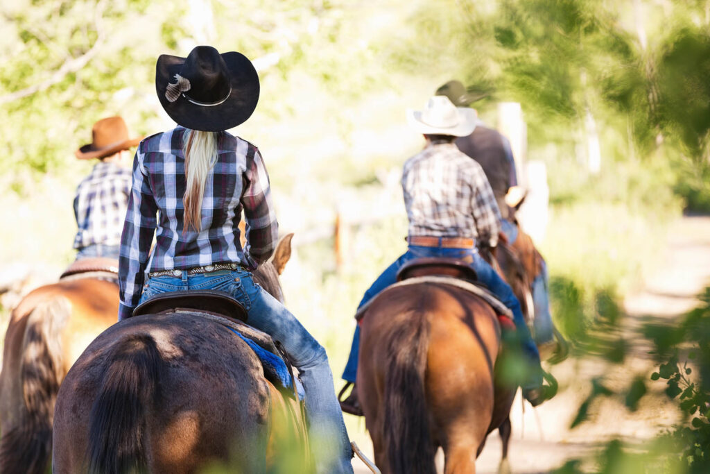 Group of ranchers riding horses together outdoors at ranch